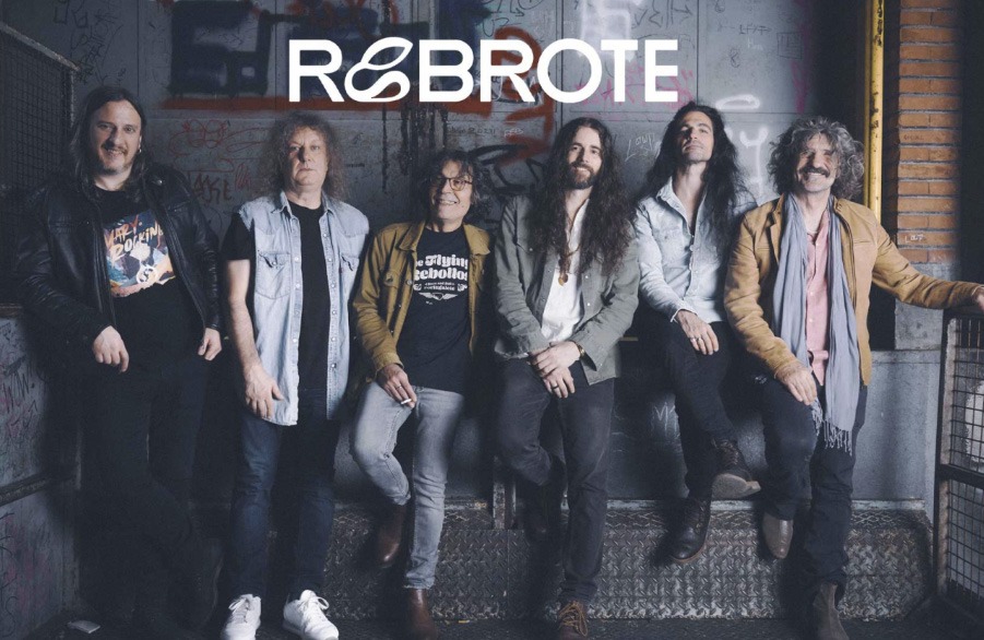 Retrato grupal de los seis integrantes de la banda de rock española Rebrote posando de pie frente a una pared con grafitis, bajo el logotipo del grupo en letras blancas.