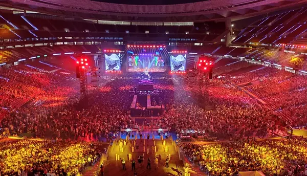 Gran multitud de asistentes disfrutan de un concierto nocturno masivo en el estadio Riyadh Air Metropolitano de Madrid, con pantallas gigantes, juego de luces rojas y un escenario espectacular en directo.