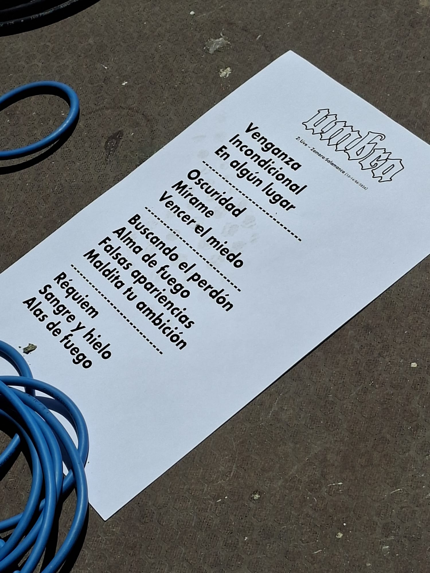 Papel impreso con la lista de canciones o setlist del concierto del grupo Umbra en el suelo del escenario.