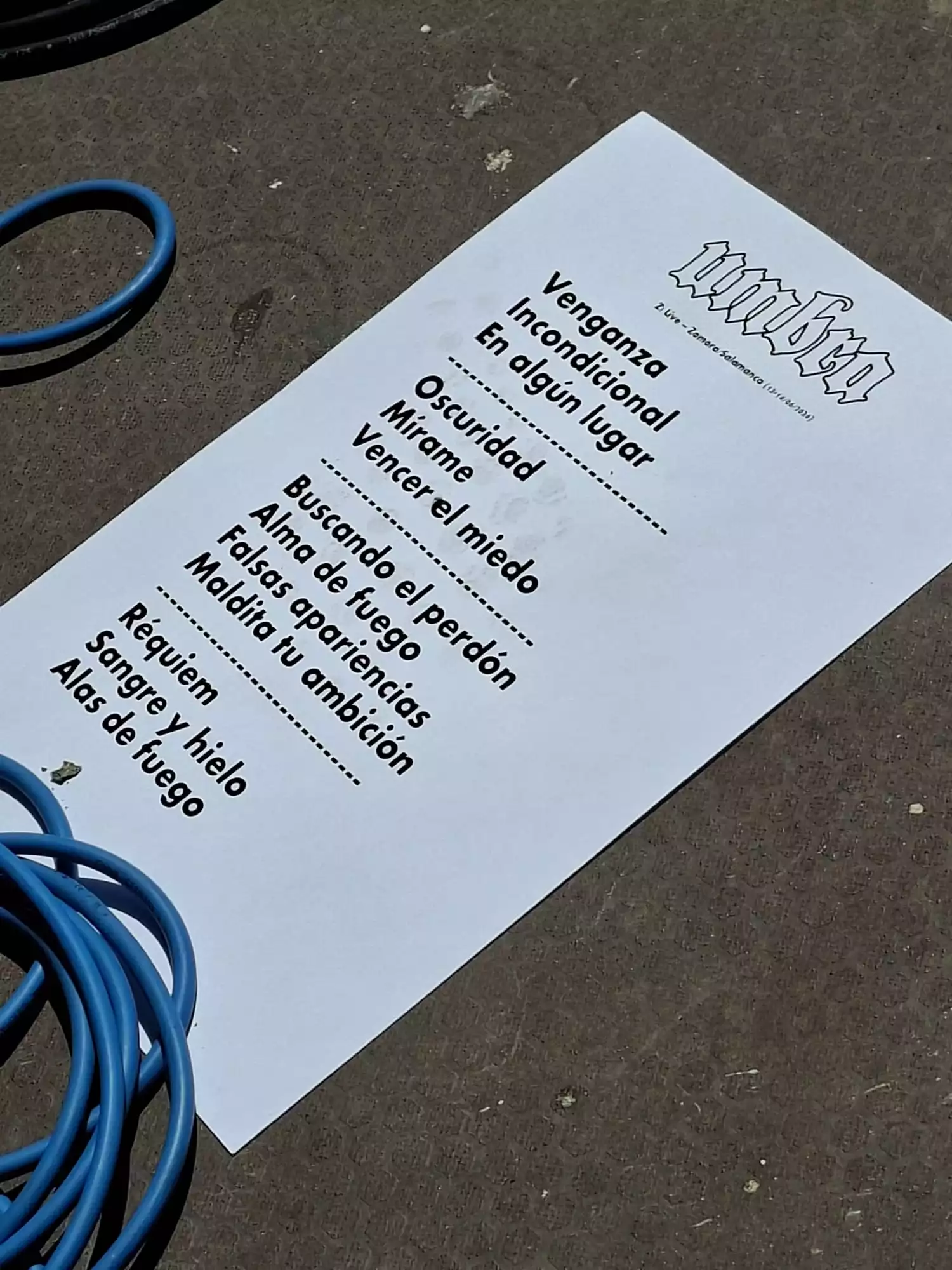 Papel impreso con la lista de canciones o setlist del concierto del grupo Umbra en el suelo del escenario.